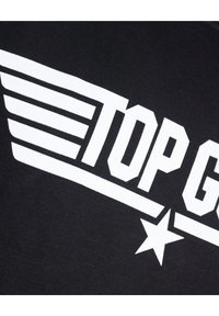 Zwarte katoenen T-shirt met gedurfde witte grafische tekst "TOP GUN" en accenten van vleugels en sterren, met de nadruk op een strakke, sportieve uitstraling.