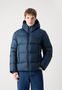 Tamnoplava puffer jakna s kapuljačom, koja ima zatvarač i kvadratni kviltani uzorak. Uključuje mali logotip na prsima.