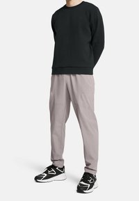 Svart sweatshirt med rund hals, kombinerad med ljusgrå tapered byxor. Svarta sneakers har vita detaljer och en sportig design.