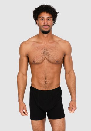 Black boxer shorts made of cotton with a snug waistband. The design includes a front pouch and mid-thigh length. Texture appears smooth.