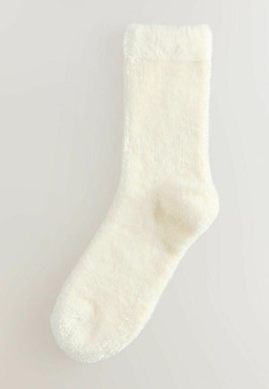 Ciorap de culoare crem, cu o textură pufoasă și moale, având un tiv pufos și vârful rotunjit. Fără modele sau accente vizibile.