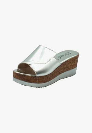 Sandalo con tacco a cuneo aperto in argento metallico, con una base simile a sughero e suola bianca. Presenta una parte superiore liscia e una fascia larga che attraversa il piede.