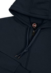 Felpa con cappuccio blu navy, dotata di zip completa, lacci con punte in metallo e un'etichetta con il nome del brand "Colmar". Tessuto dalla texture liscia.