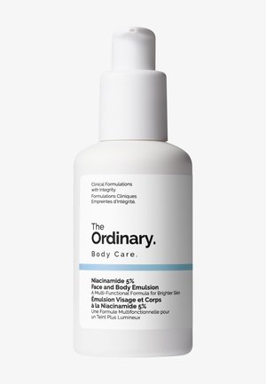 Vit flaska med pumpdispenser. Etiketten har svart text och ett blått streck. Produktnamn: "The Ordinary Niacinamide 5% Ansikts- och Kroppsemulsion."