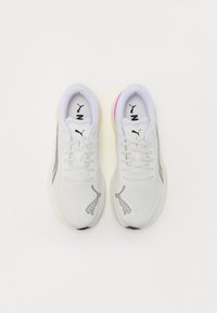 Zapatillas deportivas blancas con parte superior de malla, acentos negros y un logo gris prominente en los laterales. Presenta una suela texturizada y acentos de color en el talón.