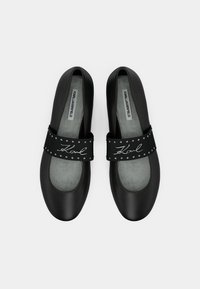 Czarne baletki z gładką powierzchnią, ozdobione szerokim czarnym paskiem z srebrnymi ćwiekami i wyszywanym napisem, zaokrąglony nosek.