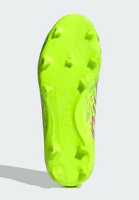 Suela de botas de fútbol verdes con una superficie texturizada, que cuenta con seis clavos prominentes y la palabra "PREDATOR" moldeada en el diseño.
