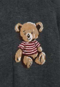 Szary sweter z dzierganym wzorem misia z brązową głową i kończynami, ubranego w czerwono-białą, paskowaną koszulkę.