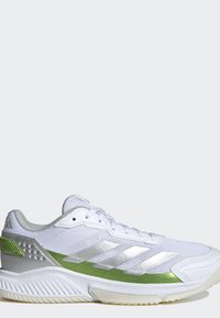 Scarpa sportiva bianca con dettagli verde chiaro e argento, tomaia in mesh e suola testurizzata, vista di profilo su sfondo semplice.