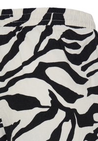 Gros plan sur un tissu avec un motif zèbre noir et blanc et une ceinture élastique, probablement une partie d’un vêtement.