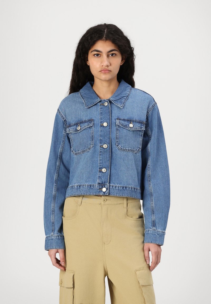 Blyanse denimjakke med kort lengde, med knappestykk foran, to brystlommer og en klassisk krage med knappdetaljer.