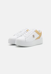 Białe sneakersy z faux skórki z teksturowanym, wypukłym obcasem i złotym akcentującym panelem. Posiada białe sznurówki i małe logo po boku.