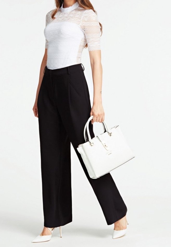 Haut blanc en dentelle à manches courtes associé à un pantalon noir taille haute à jambes larges. Sac cabas blanc avec des accents argentés et des escarpins blancs pointus.