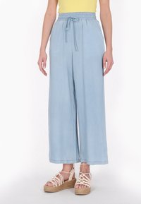 Lichtblauwe broek met wijde pijpen, voorzien van een elastische tailleband en trekkoord. Zacht stof met een gladde textuur, afgewerkt met een eenvoudige zoom.