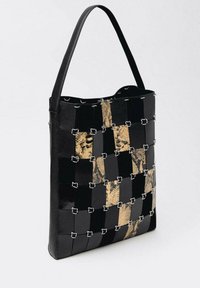 Zwarte en beige gevlochten tas met een glanzende afwerking, voorzien van een opvallend slangpatroon, verstelbare schouderriem en accenten in zilvermetallic.