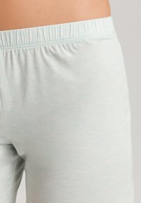 Světlé modré, měkké šortky z látky s elastickým pasem, s texturovaným, mírně skvrnitým vzorem. Nejsou viditelné žádné kapsy.