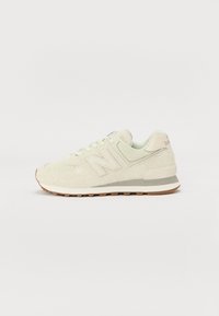 Vaaleanvihreät New Balance -lenkkarit, joissa on teksturoitu yläosa, pehmeää mokkaa ja verkkomateriaaleja sekä kumipohja ruskeilla yksityiskohdilla.
