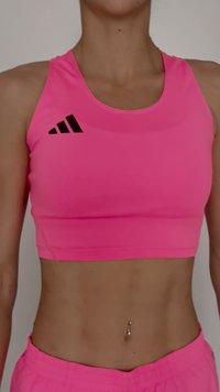 Rožinė sportinė trumpa palaidinė su aptemptu dizainu, ant krūtinės esantis juodas Adidas logotipas. Lygus paviršius ir minimalistinis stilius.