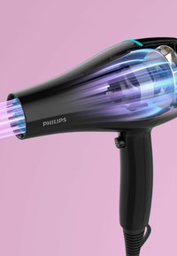 Il phon Philips presenta un corpo nero elegante, un grande beccuccio che emette un flusso d'aria blu e una maniglia antiscivolo per una facile impugnatura.