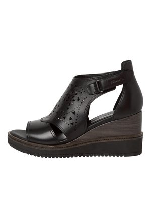 Sort læder kilesandal med udskårne mønstre, justerbar ankelrem, åben tå og tekstureret kilehæl. Let buet design.