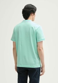 Mintgrön pikétröja i bomull med korta ärmar, klassisk krage och kontrasterande kant vid ärmsluten.