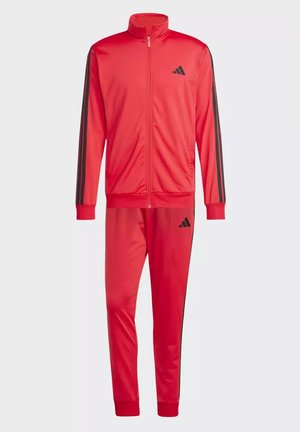 Completo tuta rossa realizzato in tessuto liscio, con giacca con zip e pantaloni abbinati. Strisce nere sulle maniche e sui lati, logo sul petto.