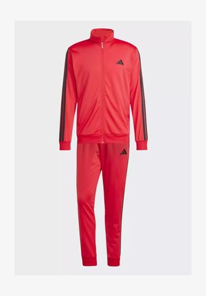 Completo tuta rossa realizzato in tessuto liscio, con giacca con zip e pantaloni abbinati. Strisce nere sulle maniche e sui lati, logo sul petto.