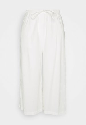 Pantaloni culotte bianchi, larghi, realizzati in tessuto leggero. Presentano una vita elastica con cordoncino e tasche laterali.