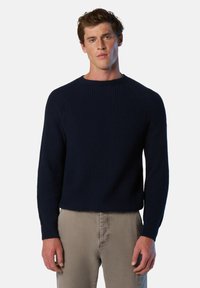 Suéter de punto acanalado en color marino con mangas largas y cuello redondo. Presenta un tejido texturizado y un diseño de mangas raglán, combinado con pantalones de color claro.