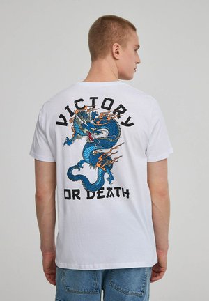 T-shirt bianco in cotone con un grafico di drago blu con fiamme e il testo "VITTORIA O MORTE" in grassetto nero sul retro.