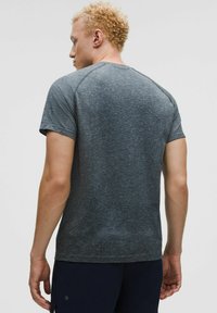 Koszulka sportowa z krótkim rękawem w ciemnoszarym kolorze, z teksturowanym wzorem i rękawami raglanowymi, z dyskretnym logo na rękawie.