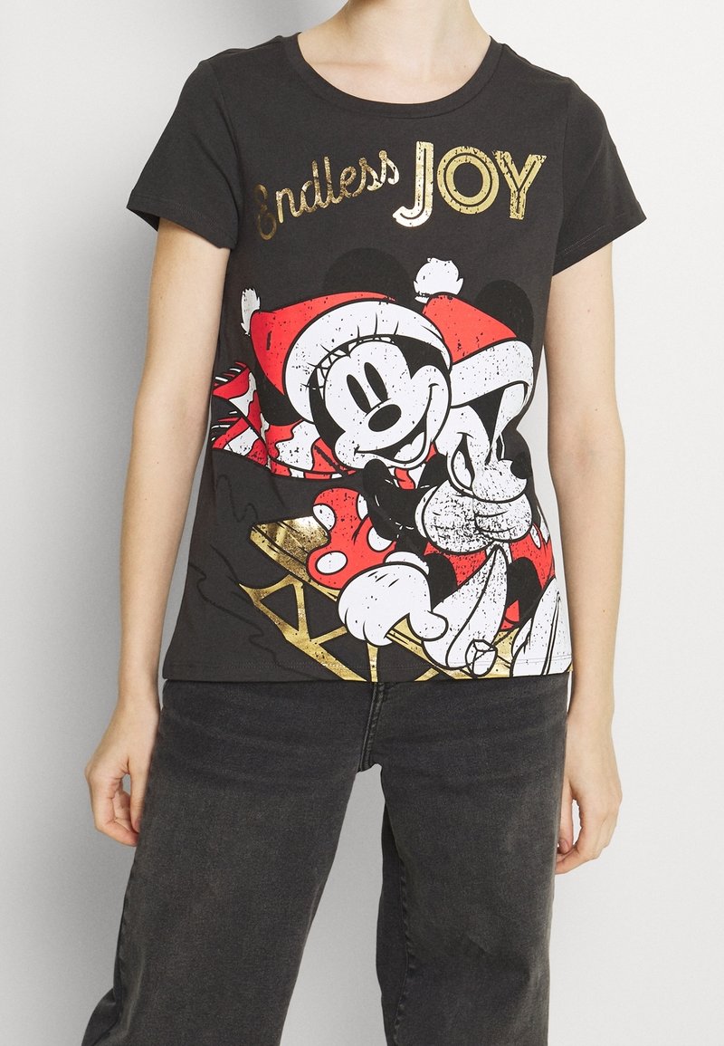 Personne portant un t-shirt noir avec Mickey et Minnie Mouse en chapeaux de Père Noël s'enlaçant, avec le texte doré « Joie éternelle » au-dessus des personnages.
