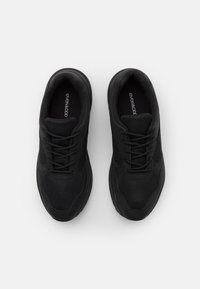 Chaussures de sport noires avec une tige en maille texturée et des accents en cuir lisse. Présentent un laçage symétrique et un col rembourré pour le confort.