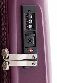 Valigia rigida viola con lucchetto a combinazione, quadranti numerici e serratura approvata TSA; zip metallici con logo.