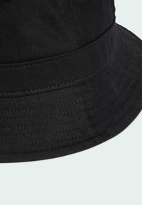 Black bucket hat made of textured fabric, featuring a wide brim and structured crown with visible stitching details.