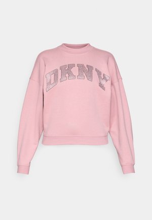 Ružová skrátená mikina s dlhými rukávmi a okrúhlym výstrihom. Na hrudi sa nachádza kovový potlač loga "DKNY". Mäkká textúra.