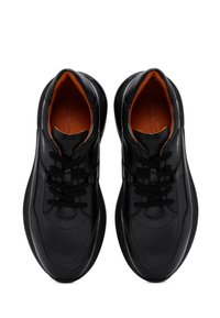 Sneaker in pelle nera con texture intrecciata, punta rotonda, lacci neri, rivestimento interno arancione, suola supportiva e un sottile dettaglio di branding sulla linguetta.