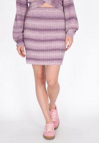 Gestreifte lila Strickröcke mit Rippstruktur, kombiniert mit rosa Sneakers mit strukturiertem Material und hellen Schnürsenkeln.