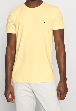 Yellow cotton t-shirt with a round neckline and short sleeves, featuring a small embroidered logo on the left chest. Soft texture.