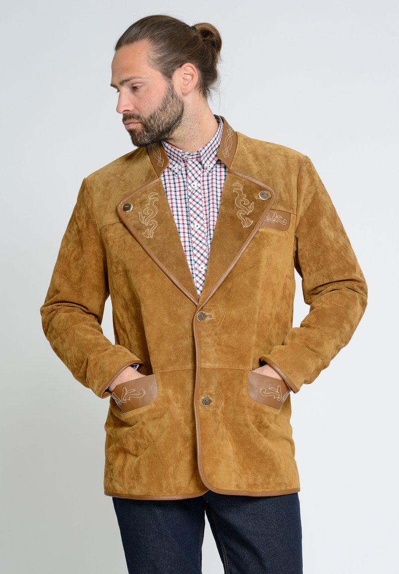 Bruine suède jas met contrasterende leren accenten en ingewikkelde lichte borduursels. Beschikt over twee voorzakken en een op maat gemaakte kraag.