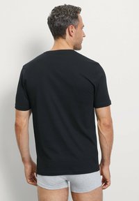 Zwarte korte mouw t-shirt gemaakt van zachte stof, met een klassieke ronde hals en een gladde textuur, weergegeven vanaf de achterkant.