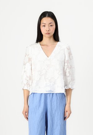 Witte blouse met bloemenpatroon, een V-hals en pofmouwen, gecombineerd met lichtblauwe textuurbroek. Zacht, lichtgewicht materiaal.