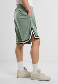 Lysegrønne sportsshorts med sorte og hvide detaljer, der har en komfortabel talje og sidelommer. Glat, åndbart materiale.