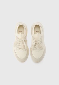 Baskets beige clair avec des panneaux en maille texturée et en daim, dotées d'un bout arrondi, de lacets plats et d'un logo subtil sur la semelle intérieure.