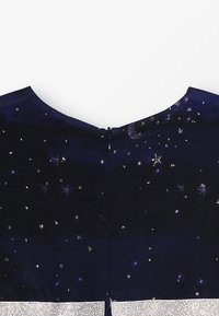 Abito navy con un motivo stellato e un accento argento all'orlo. Tessuto liscio con chiusura posteriore a zip e scollo ampio.