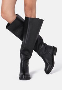 Zwarte leren laarzen tot de knie met een gladde afwerking en een licht slouchy ontwerp. Ronde neus en een lage gestapelde hak zorgen voor een klassieke uitstraling.