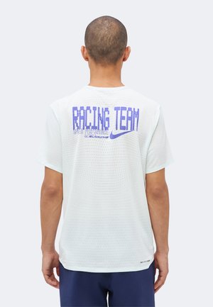 Homme aux cheveux courts portant une chemise blanche à manches courtes perforée avec le texte bleu "RACING TEAM" et le logo Nike dans le dos.