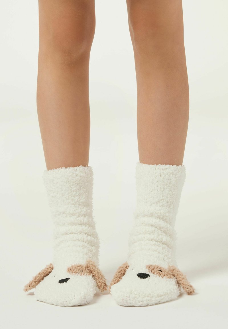 Calzini bianchi soffici con design di cane, texture morbida, vestibilità morbida, con accenti color beige per le orecchie e occhi e naso ricamati in nero.