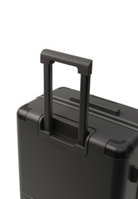 Zwarte harde koffer met een uitschuifbare dubbele handgreep, afgeronde hoeken en versterkte randen. Glad oppervlak met een minimalistisch ontwerp.