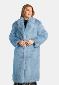 Cappotto lungo in pelliccia sintetica azzurro chiaro con ampio colletto, vestibilità leggermente over e texture morbida. Presenta grandi polsini e una chiusura frontale.